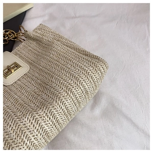 Macro shot of beige woven tote featuring white leather trim and gold twist lock closure