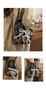 Close-up of leopard print pillow bag with lace bow, pearl heart charm and cherry decor