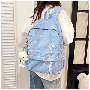 Close-up of light blue quilted school backpack featuring colorful embroidered bows