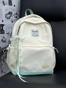 Close-up of cream canvas backpack with green accents and heart lace bow charm