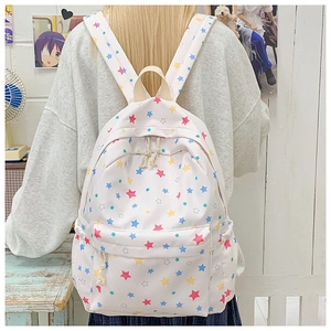 Close-up of a white canvas backpack with colorful star prints and side water bottle pocket