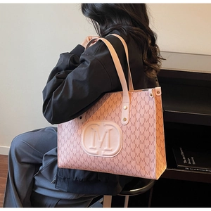 Detail of pink tote bag showing the embossed letter M logo and monogram pattern print