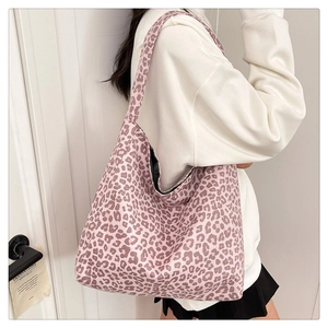 Pink leopard print suede tote bag worn on shoulder by model in casual white hoodie