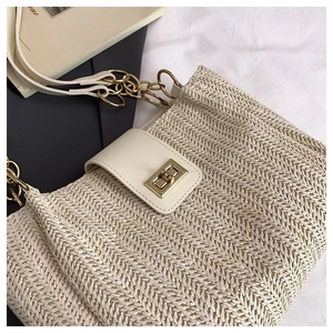 Detail of woven straw shoulder bag featuring a golden twist lock and beige leather flap