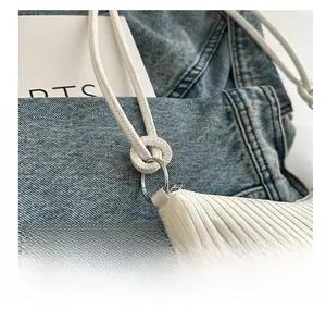 Gros plan du sac en cuir blanc plissé montrant l'anneau en métal argenté et la bandoulière