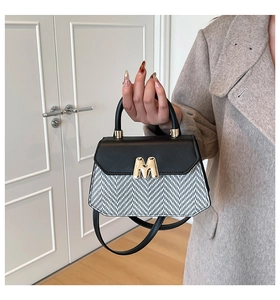 Gros plan détaillé du sac à main tissé avec boucle en métal doré M et poignée noire