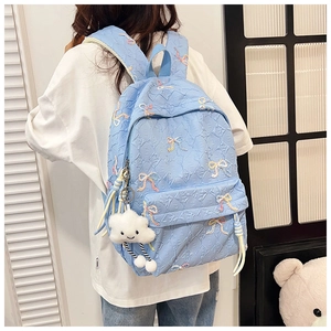 Detail of light blue quilted backpack featuring colorful butterfly embroidery and plush charm