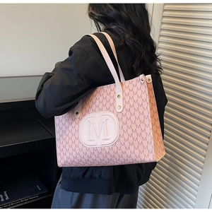 Detail view of pink textured tote bag with repetitive M jacquard pattern and large round logo
