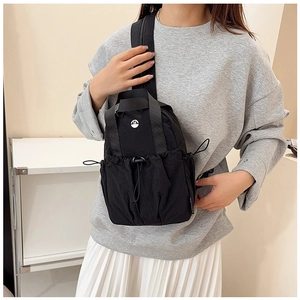 Close-up of black nylon chest bag with drawstring pocket and white letter M logo