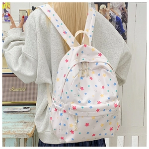 Rear view of cream backpack with colorful star patterns worn by model in cozy room