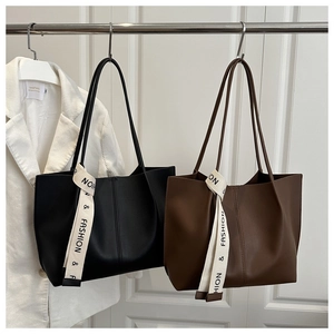 Detail of black and brown tote bags with matte finish and fashion ribbon tag