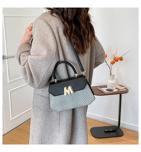 Détail d'un sac élégant à motif pied-de-poule avec fermoir doré M et poignée en cuir