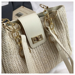 Detail of herringbone straw weaving texture and golden twist lock on cream tote bag