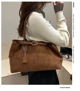 Detail view of large dark brown suede tote bag featuring a decorative gold metal buckle