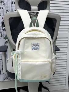Close-up of white canvas backpack with mint green panel and lace ribbon decoration