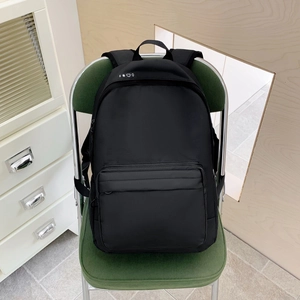 Minimalist black canvas backpack with geometric icons on a green chair in home setting