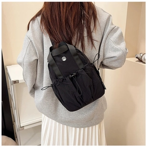 Rear view of a model wearing a lightweight black nylon backpack with drawstring closure