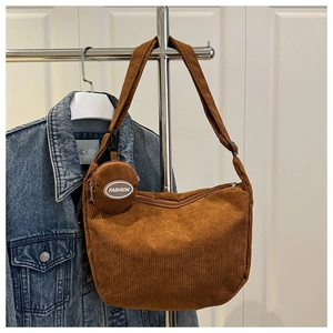 Detail of brown corduroy tote bag with small round coin purse hung on a metal rack
