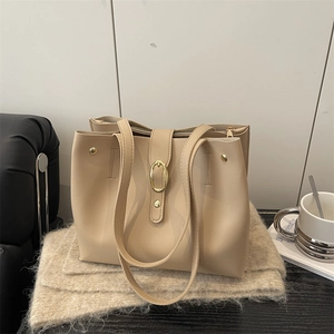 Retro beige leather tote bag with gold buckle and rivets in a lifestyle setting