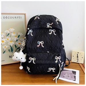 Detail of black quilted backpack with embroidered colorful bows and cute cloud charm