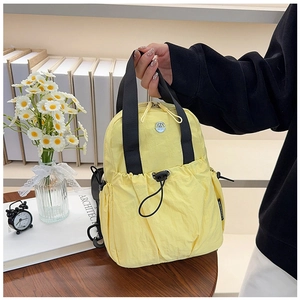 Detail of yellow nylon backpack featuring black drawstring pocket and durable fabric texture