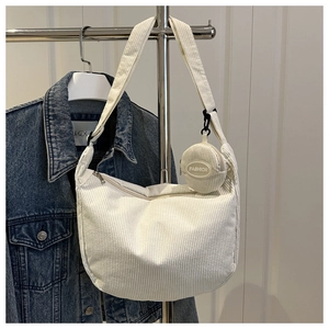 Detail of hobo bag in cream corduroy fabric with a small round coin purse charm