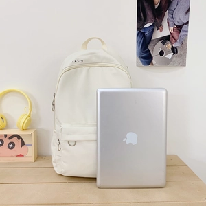 Minimalist cream canvas backpack for students featuring a laptop compartment and front pockets