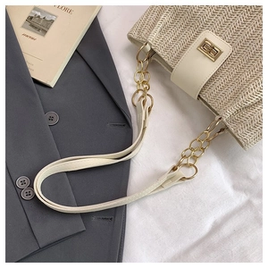 Detail of woven straw tote bag with metallic turn-lock closure and gold chain strap