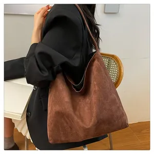 Close-up of brown suede tote bag texture with minimalist hobo shoulder strap design