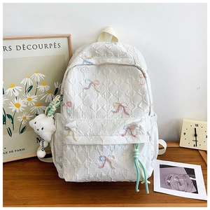 Detail of white quilted backpack with colorful bow embroidery and cloud plush charm