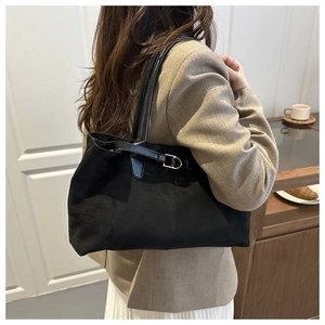 Detail view of large black faux suede tote bag with leather straps and metal buckles
