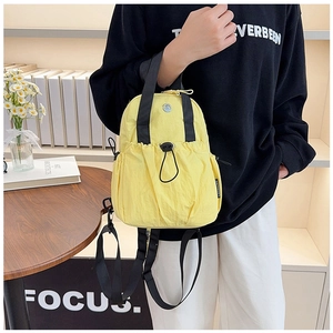 Detail view of a yellow waterproof nylon mini backpack featuring a drawstring front pocket