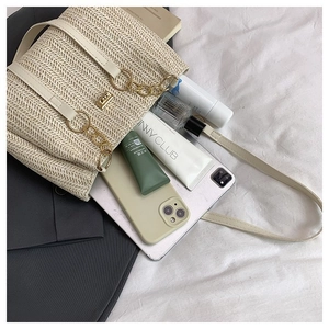 Detail view of woven straw tote bag texture with leather strap and golden buckle