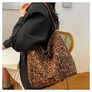 Detail of a large leopard print tote bag styled with a black blazer and white skirt