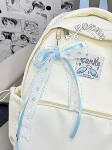 Close-up of cream canvas backpack with blue ribbon bow and lace heart accessory detail