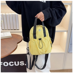 Close-up of bright yellow mini nylon backpack with drawstring pocket and black handle