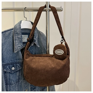 Detail of a brown corduroy crescent bag with a round mini pouch and silver fashion label