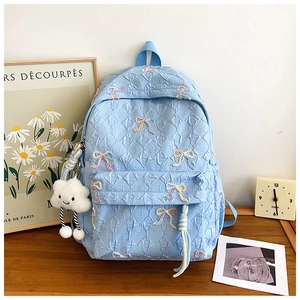 Detail of light blue quilted backpack with bow embroidery and plush cloud pendant charm