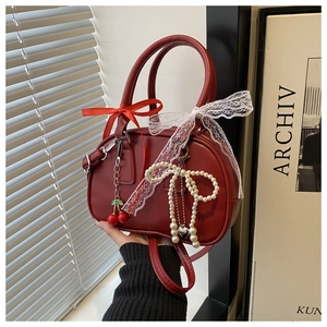 Detail of dark red vintage bow-knot handbag with cherry pendant and pearl charms