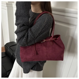 Close-up of burgundy faux suede tote bag with matching glossy handle and buckle detail