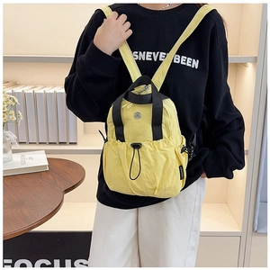 Detail view of yellow nylon backpack with contrast black straps and drawstring front pocket