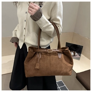 Detailed view of brown suede tote bag with metal buckle worn on the shoulder