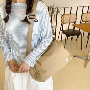 Large khaki nylon crescent bag for commuting with wide woven strap and minimalist logo