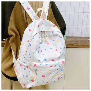 Close-up of white canvas backpack with colorful star patterns and front zip pocket