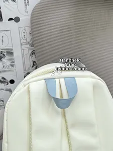 Detail of the reinforced light blue top handle and breathable mesh back on the beige backpack