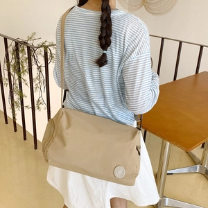 Large khaki nylon messenger bag for commuting, showing crossbody style on a model