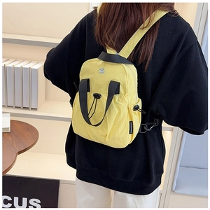 Close-up of lightweight yellow nylon backpack with drawstring and black top handle