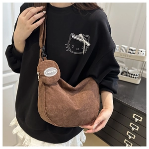 Detail of dark brown corduroy crossbody bag set with fashion coin purse on a model