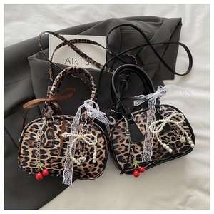 Detail of leopard print pillow bag featuring pearl bows and cherry charms decoration