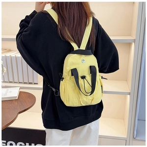 Detail view of a bright yellow nylon backpack with black straps and side storage pockets